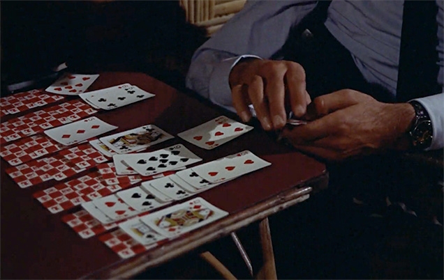 James Bond plays patience with Waddingtons Zodiac cards in Miss Taro's bedroom.