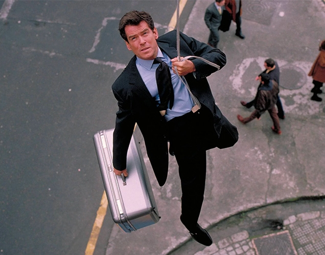 Pierce Brosnan in The World Is Not Enough, wearing a Church's Presley shoes, Brioni suit, a Turnbull & Asser tie and holding a Samsonite case.