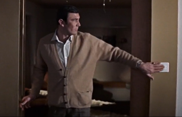 George Lazenby as James Bond wearing a light brown cardigan with two front pockets in On Her Majesty's Secret Service