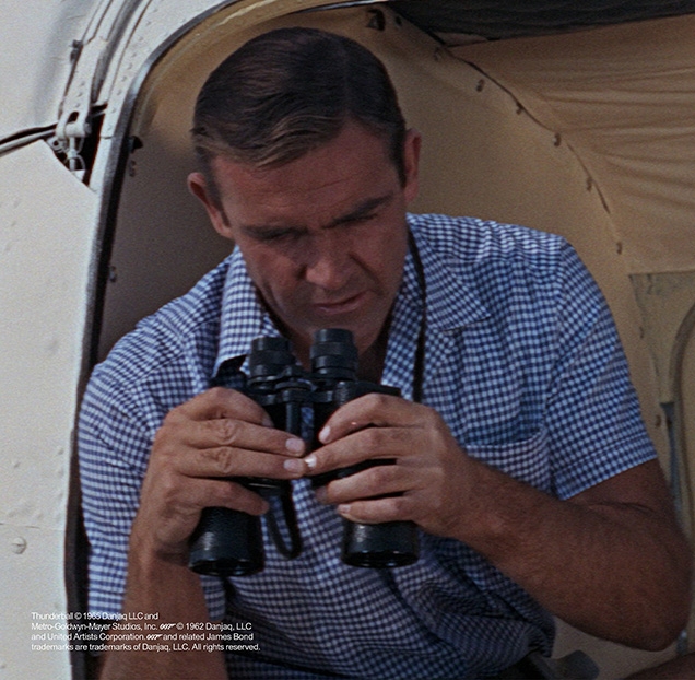 Sean Connery as James Bond in Thunderball wearing a blue Gingham shirt during the first helicopter flight with Felix Leiter
